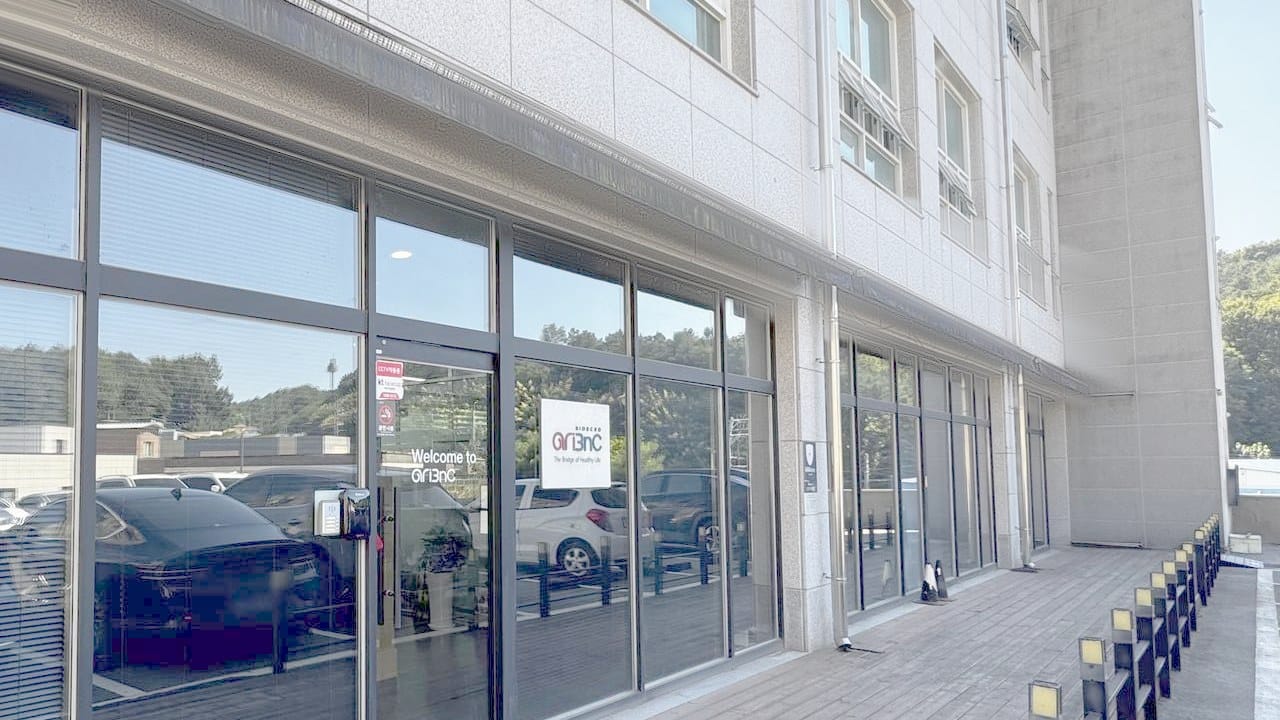용인 본사가 있는 청솔빌딩 1층 출입구. 유리문에 「Welcome to AriBnC」와 회사 로고가 붙어 있다