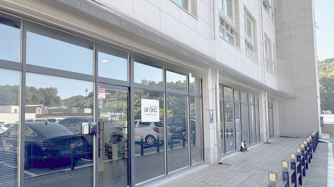 용인 본사가 있는 청솔빌딩 1층 출입구. 유리문에 「Welcome to AriBnC」와 회사 로고가 붙어 있다